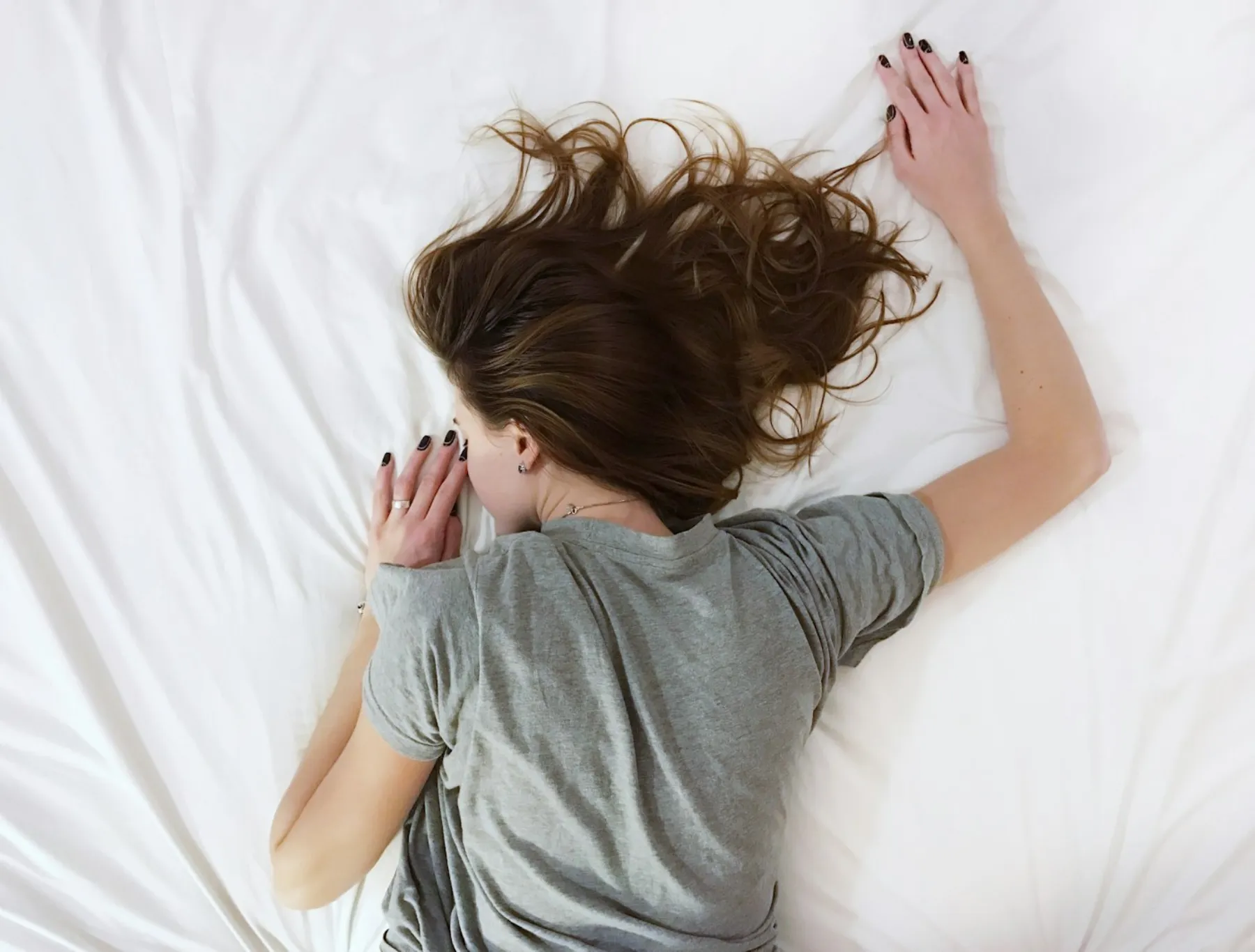 A person resting peacefully, hair spread softly across a white pillow
