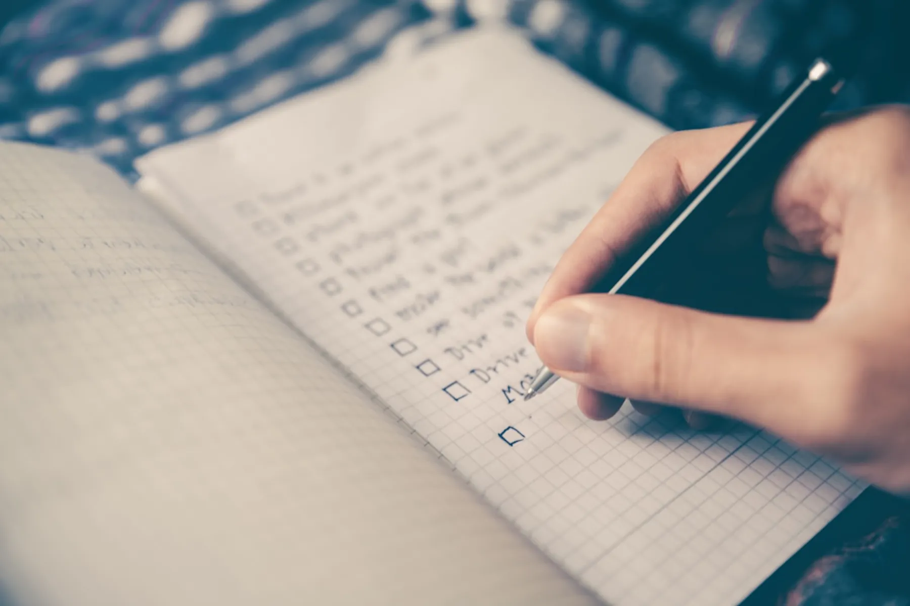 A hand writing in a journal, keeping a simple daily checklist
